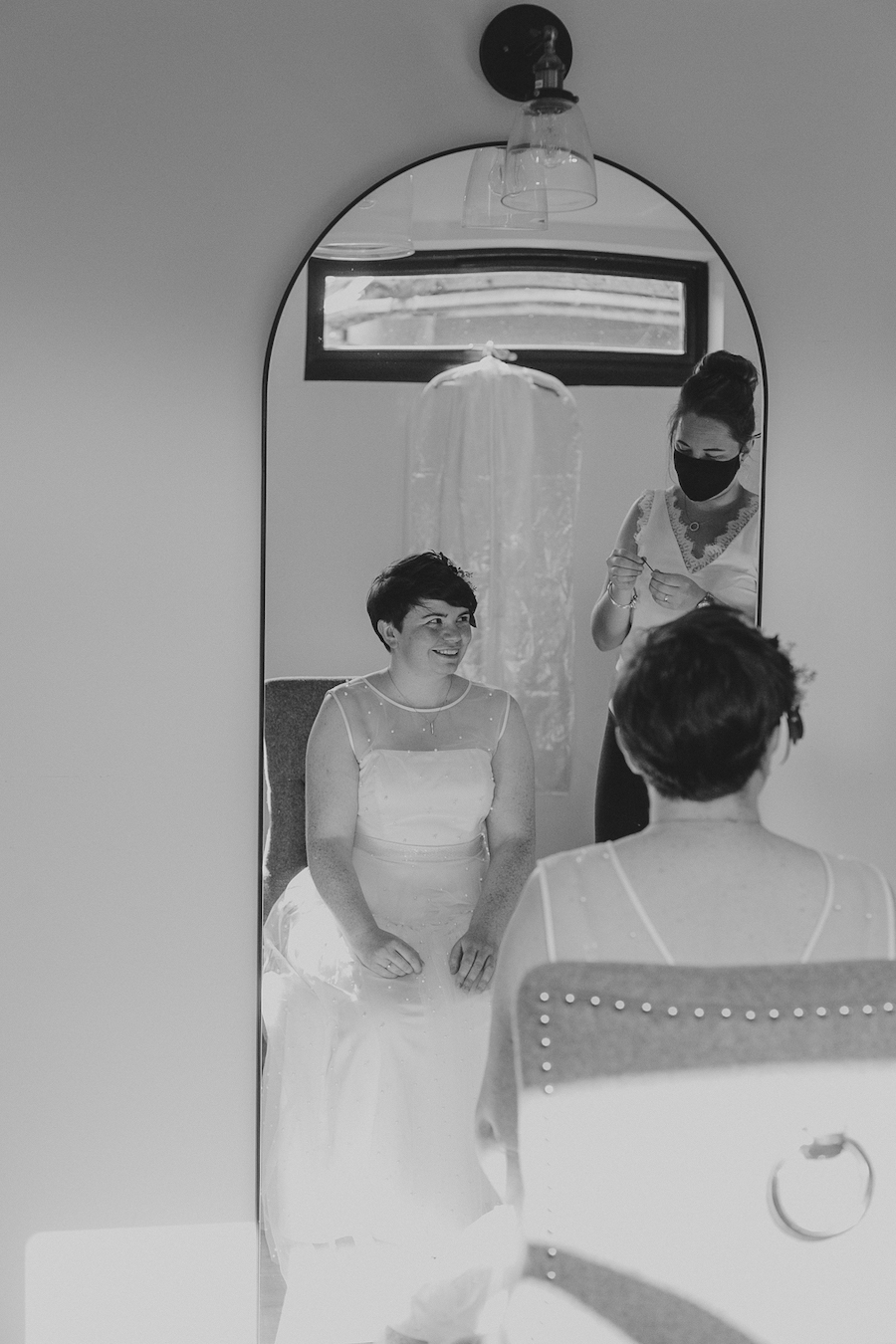 Wedding planner helping bride in front of mirror