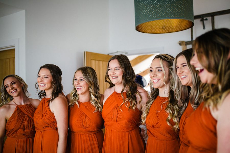 Seven happy bridesmaids in bright rusty orange dresses