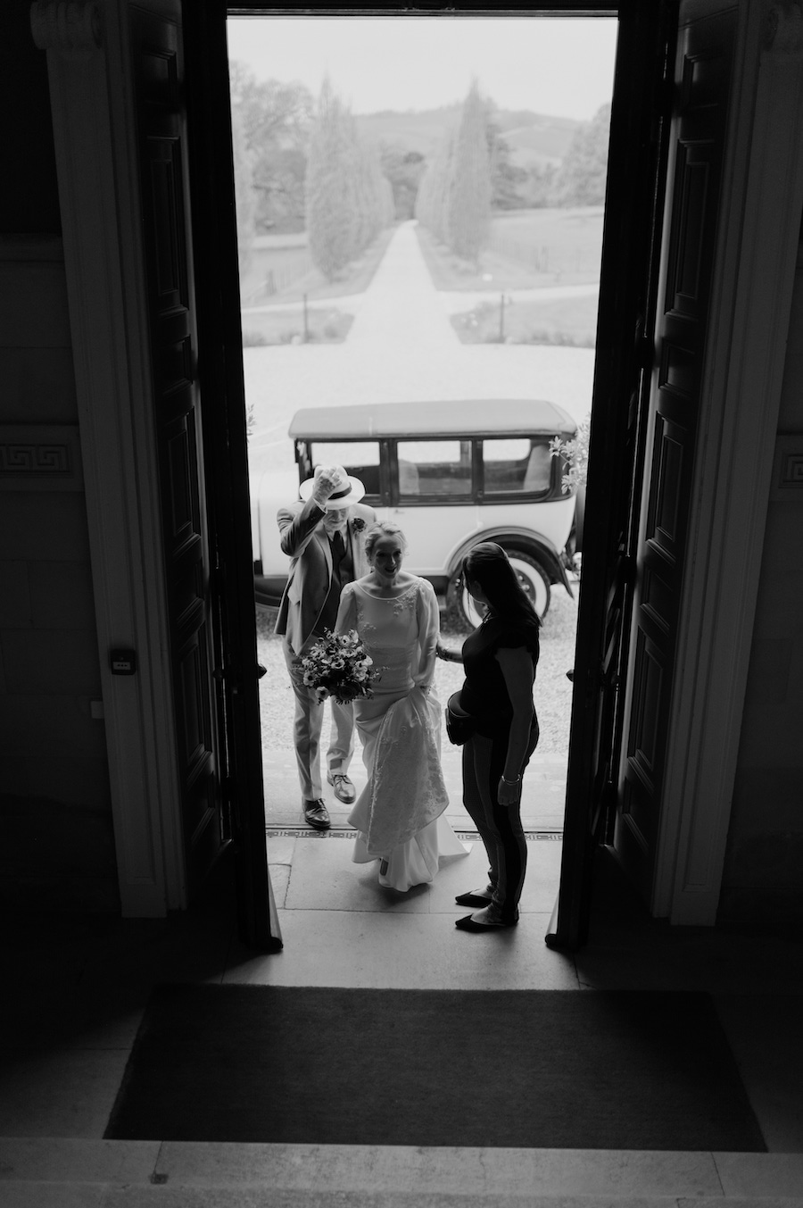 Bride arriving at a grand venue being greeted by wedding planner