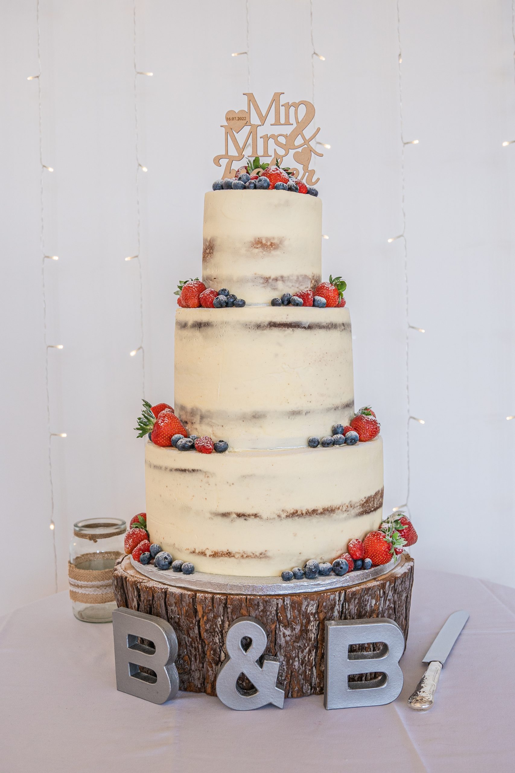 Delicious looking three tier semi naked wedding cake on a log slice ready to cut
