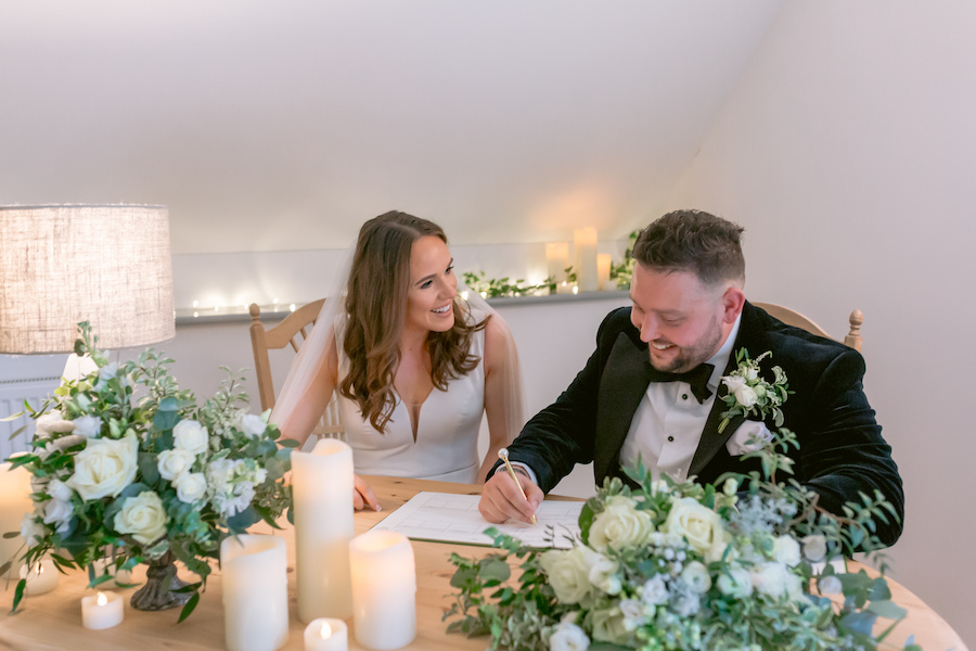Couple signing the register with beautiful flowers and candles