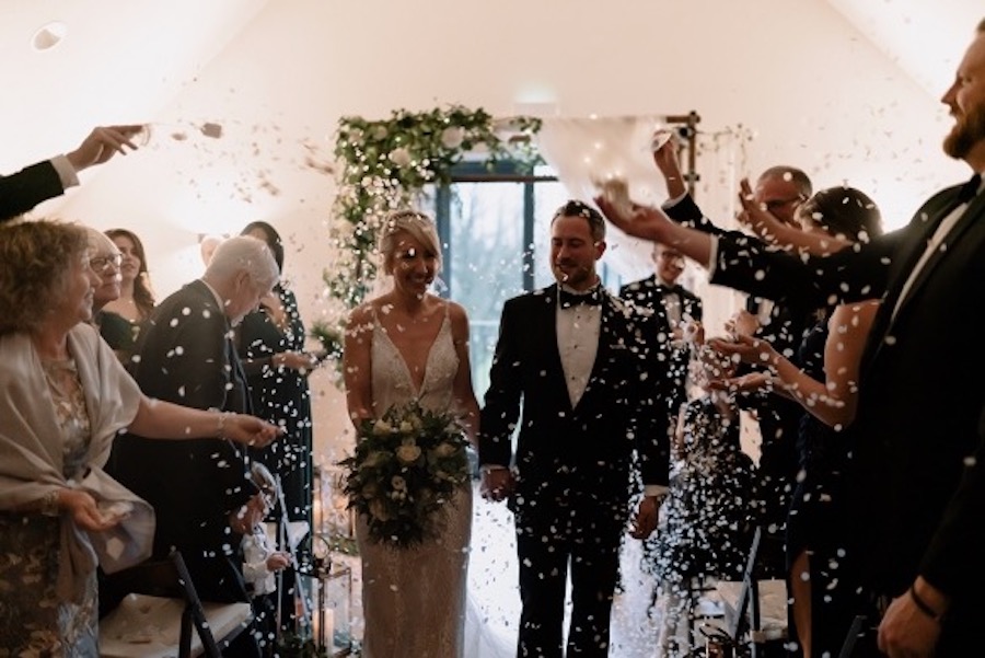 Couple exiting the ceremony room after their marriage through confetti