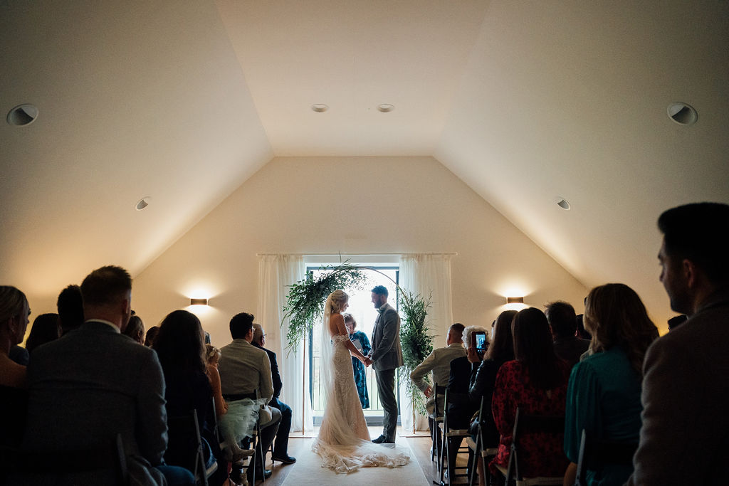 Bride and Groom during their commitment ceremony in a subtly lit ceremony room at Harefield Barn