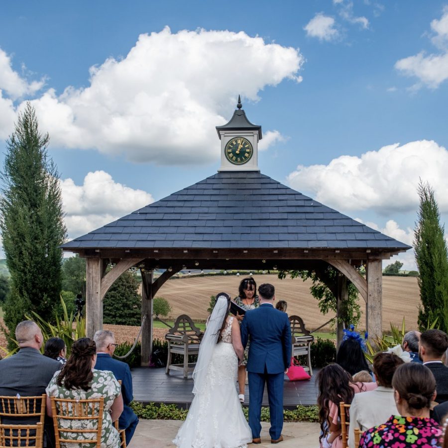 Couple have their alfresco ceremony in front of the Clock House at Harefield Barn