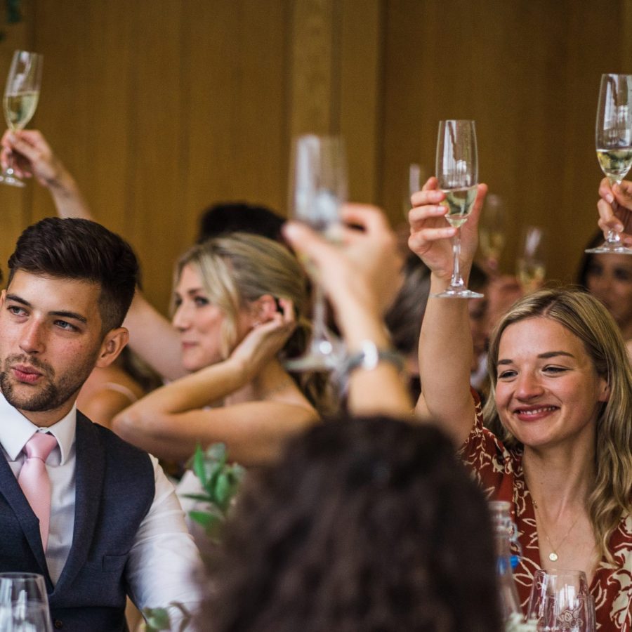 GUESTS RAISING A GLASS TO THE HAPPY COUPLE AT A WEDDING.